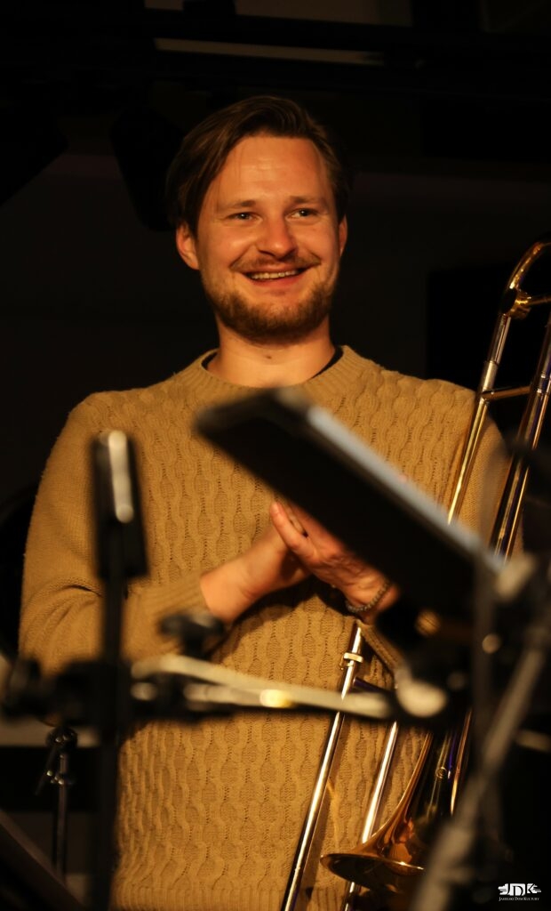 uśmiechający się puzonista w swetrze