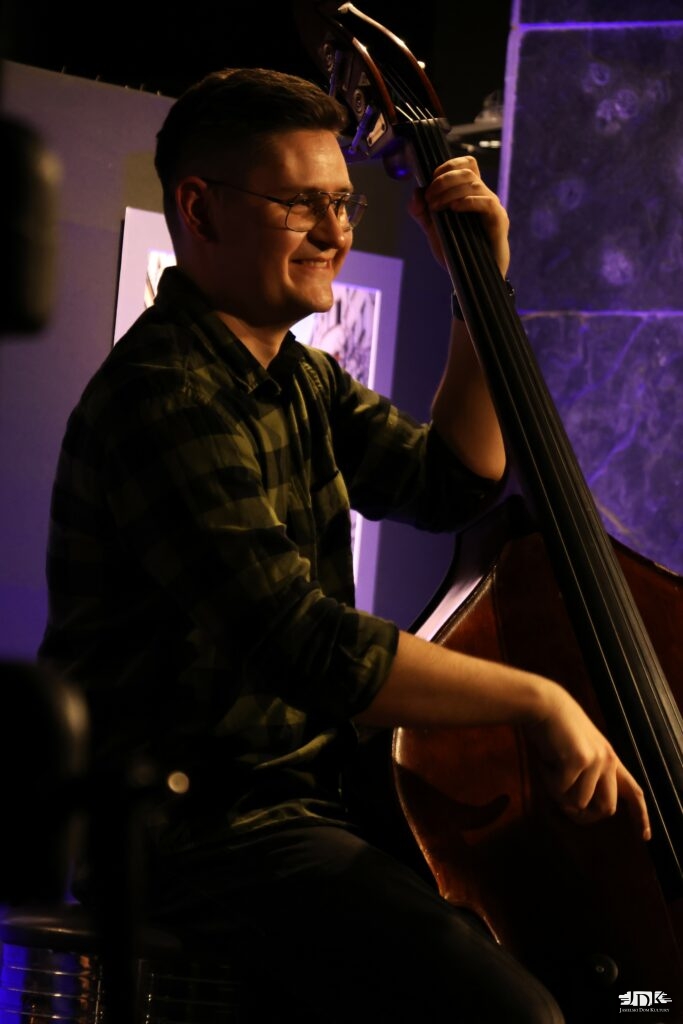 uśmiechnięty kontrabasista na fioletowym tle