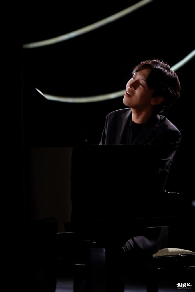 artysta z uśmiechem, grający na fortepianie