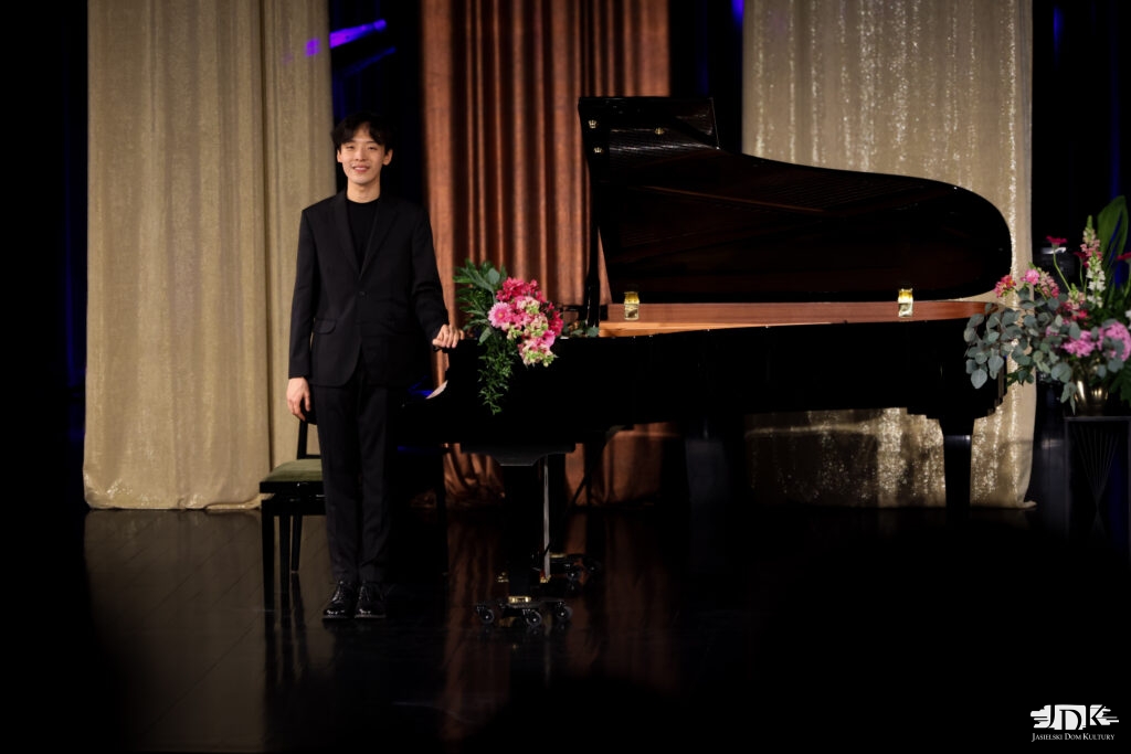 uśmiechnięty pianista przy fortepianie z kwiatami