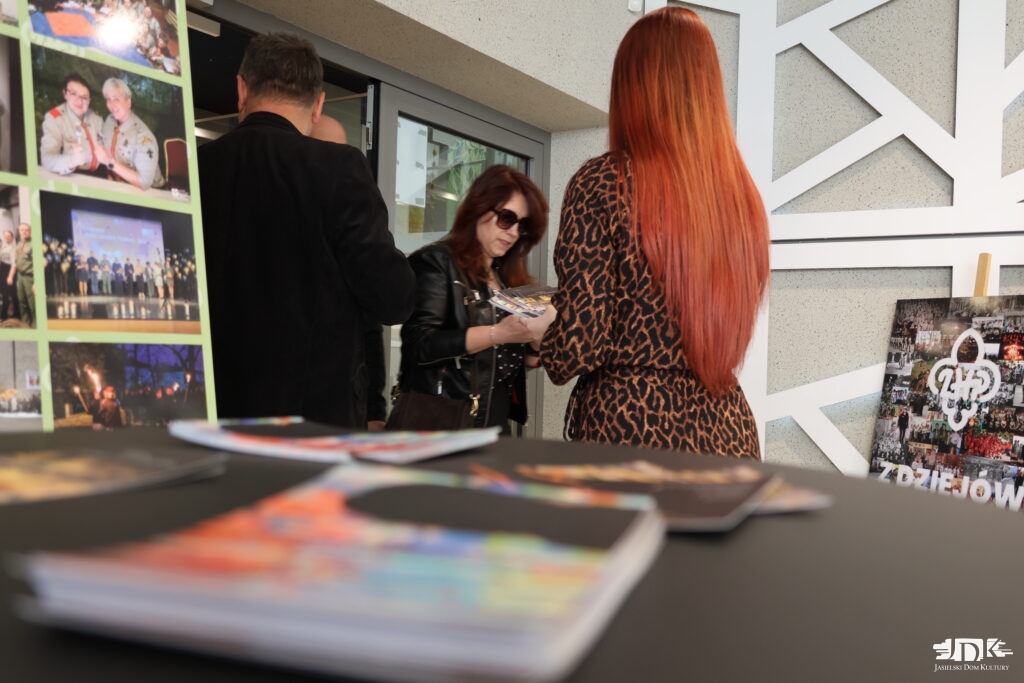 kobieta wręcza pocztówki kobiecie w ciemnych okularach