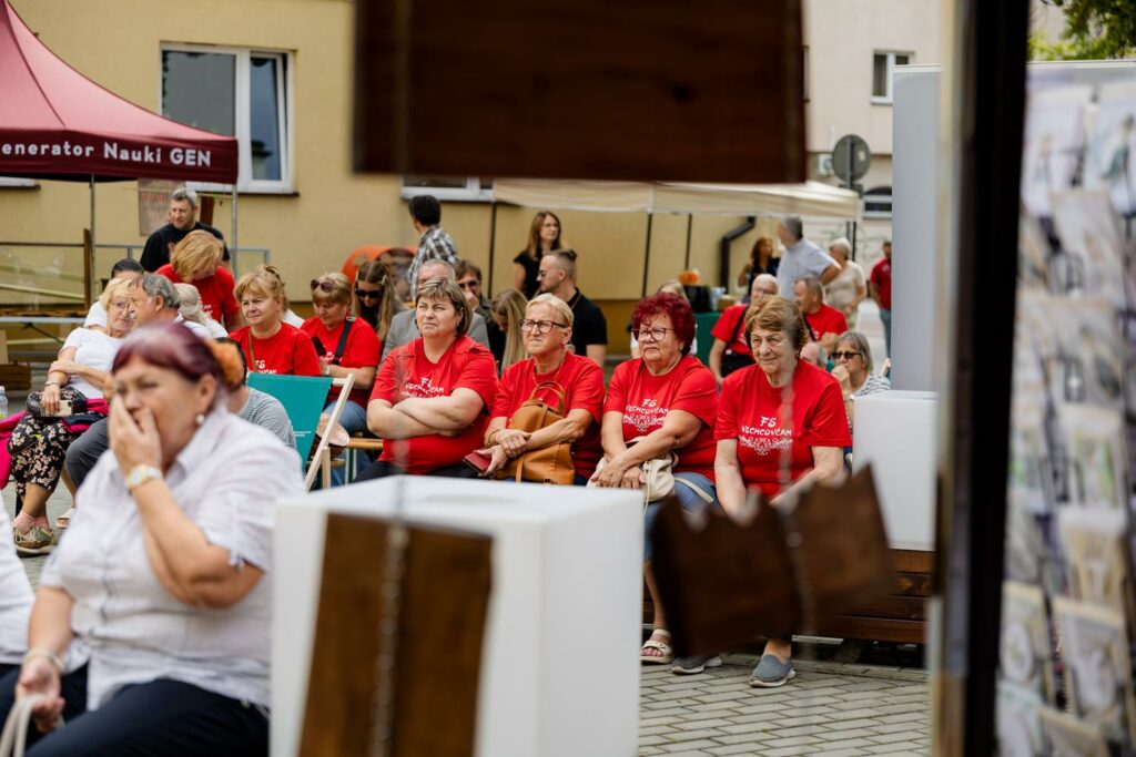 uczestnicy wydarzenia siedzący na ławeczkach