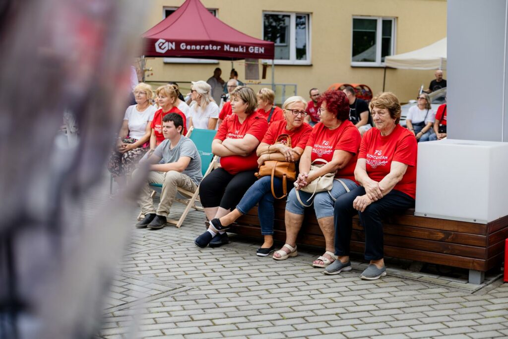 uczestnicy wydarzenia siedzący na ławeczkach