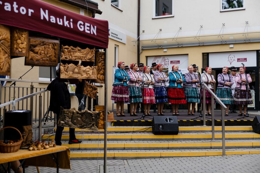 zespół pieśni i tańca w tradycyjnych strojach, tańczący i śpiewający przed budynkiem