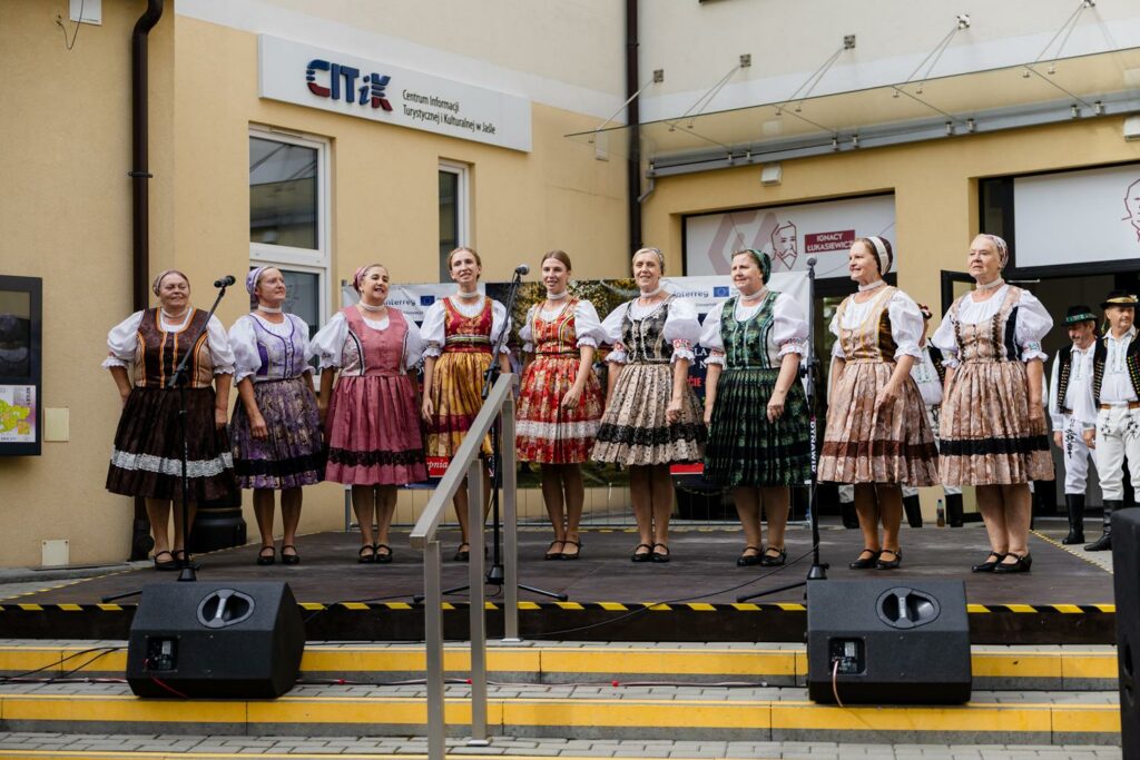 zespół pieśni i tańca w tradycyjnych strojach, tańczący przed budynkiem 