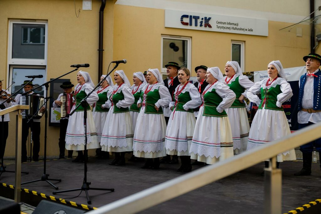 zespół pieśni i tańca w tradycyjnych strojach, tańczący przed budynkiem 